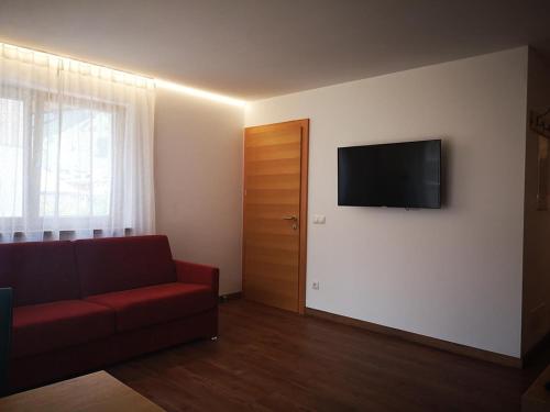 a living room with a red couch and a flat screen tv at Garni - Hotel Am Burghuegel in San Candido