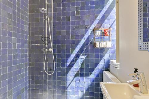 a blue tiled bathroom with a shower and a sink at Air B&B Casa Dodo in Geraardsbergen