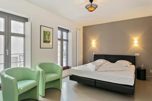 a bedroom with a bed and two green chairs at Air B&B Casa Dodo in Geraardsbergen