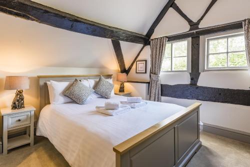 a bedroom with a large bed and two windows at The Hopton Crown in Cleobury Mortimer