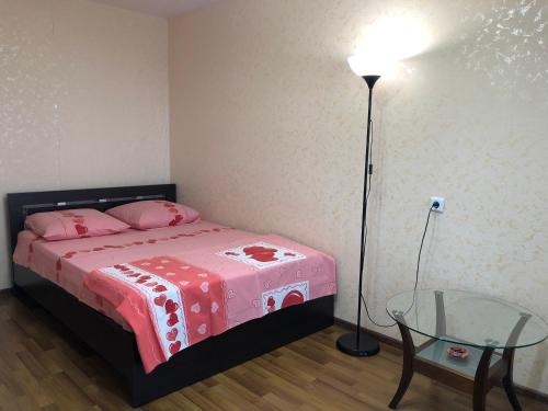 ナーベレジヌイェ・チェルヌイにあるApartment On Polyakovaのベッドルーム1室(ベッド1台、ランプ、ガラステーブル付)