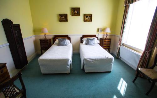 a room with two beds in a room with a window at Kilcooly's Country House Hotel in Ballybunion