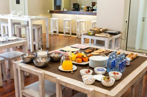 a wooden table with breakfast foods and drinks on it at Hotel Altora in Tomelloso