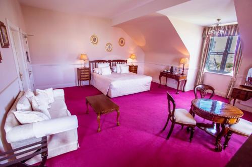 a bedroom with a bed and a table and a couch at Kilcooly's Country House Hotel in Ballybunion