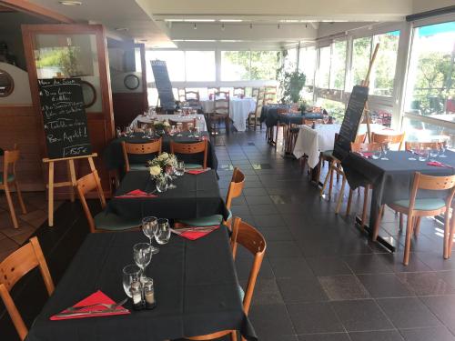 un restaurant avec des tables et des chaises noires et un chercheur de table dans l'établissement Hôtel Restaurant L'Artière, à Ceyrat