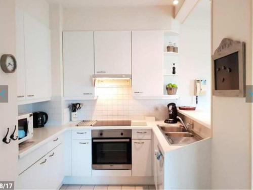 een witte keuken met witte kasten en een spoelbak bij Residentie Noordhinder - Hendrik Consciencelaan 8 - appartement G 0 08 - 8660 De Panne - België in De Panne