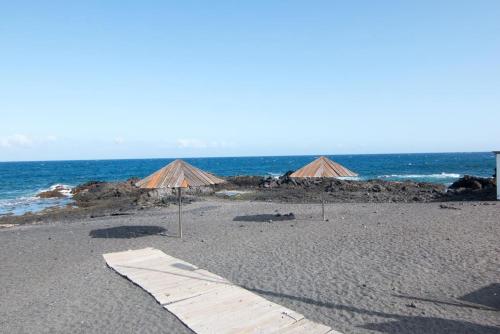 una playa de arena con sombrillas y el océano en Casa - Dias de Verano, en Malpaíses