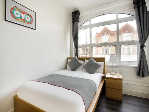 a bedroom with a bed and a large window at Broadway Inn in Southall