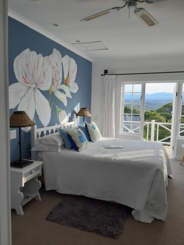 a bedroom with a white bed with a flower mural at Franmarel in Plettenberg Bay
