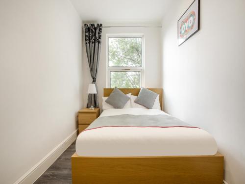 a bedroom with a large bed and a window at The Broadway Hotel - London Heathrow in Southall