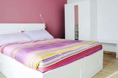a white bed with a colorful striped blanket on it at Casa dei Nonni #charminglanga in Grinzane Cavour