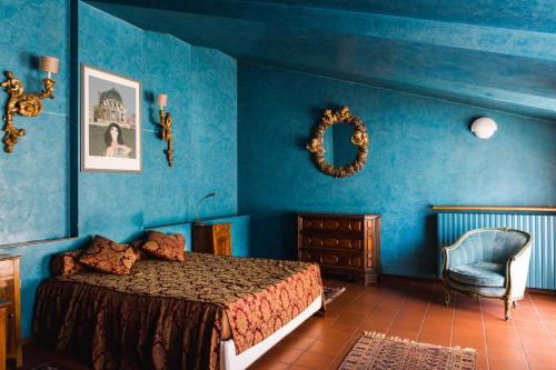 1 dormitorio con paredes azules, 1 cama y 1 silla en Locanda Da Lino en Pieve di Soligo