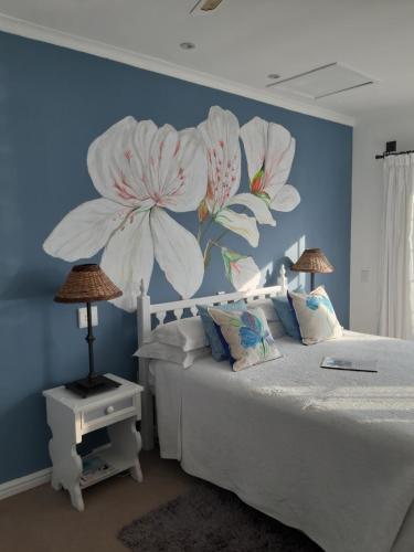 a bedroom with a bed with a flower mural on the wall at Franmarel in Plettenberg Bay