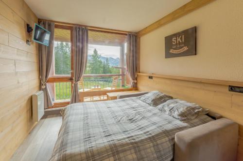 Un dormitorio con una cama y una ventana grande. en Grand Arbois, les Arcs 1800, en Arc 1800