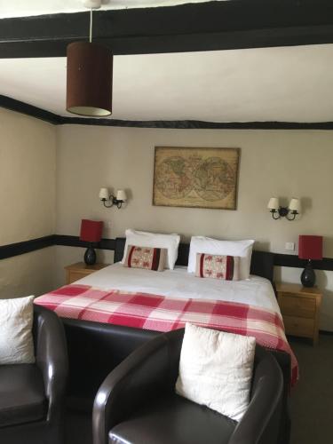 
a room with a bed, chair, table and a lamp at The Row Barge Henley in Henley on Thames

