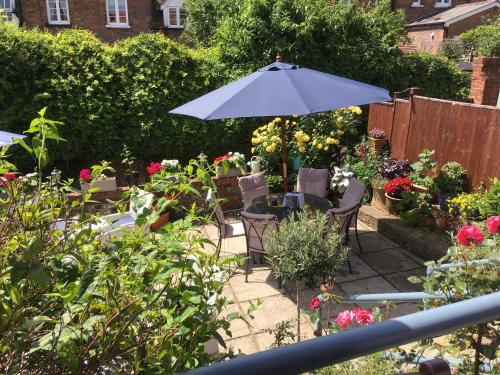 a patio with an umbrella and chairs and flowers at The Row Barge Henley in Henley on Thames