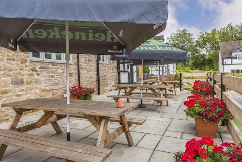 a group of picnic tables with an umbrella on a patio at The Hopton Crown in Cleobury Mortimer
