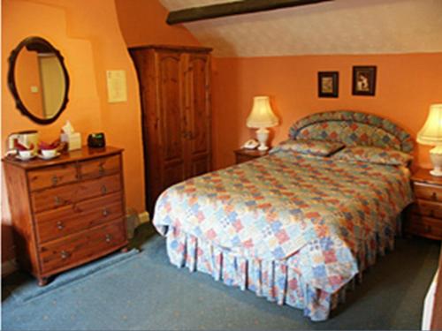 a bedroom with a bed and a dresser and a mirror at The Blacksmiths Arms in Brampton