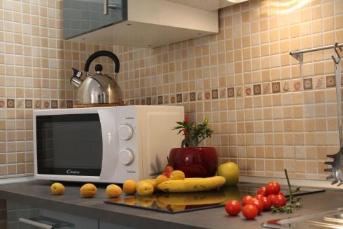 a kitchen counter with a microwave and fruits and vegetables at Appartamenti Borghetto San Donato 105 in Bologna