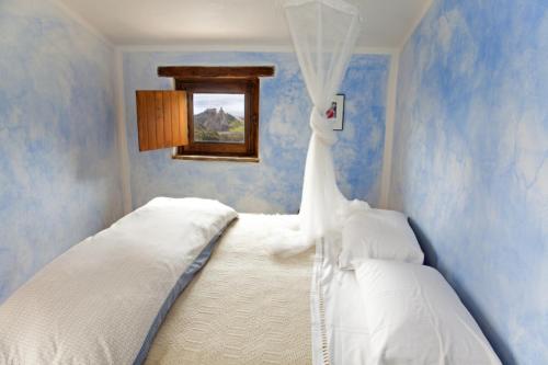 a white bed in a room with blue walls at Fondaco del Fico in Roccella Ionica