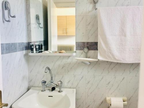 uma casa de banho branca com um lavatório e um espelho em Paradisos Studios em Pyrgi Thermis