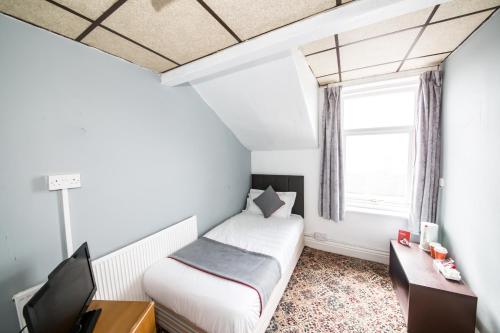 a small bedroom with a bed and a window at MyRoomz Silver Strand Hotel in Blackpool