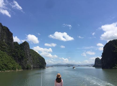 a woman on a boat in a river with mountains at Cat Ba Mystery Homestay in Cat Ba