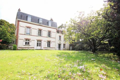 een groot wit huis met een groot grasveld bij Le Vieux Manoir in Carolles