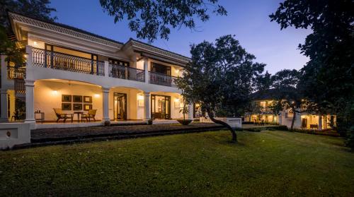 une maison avec une cour verdoyante devant elle dans l'établissement The Postcard Velha, Goa, à Vieux-Goa