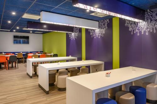 a dining room with colorful walls and tables and chairs at ibis budget Saint-Étienne Centre Gare Châteaucreux in Saint-Étienne