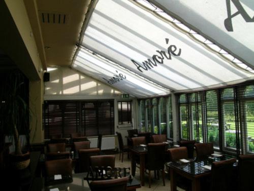 um restaurante com mesas e cadeiras numa sala com janelas em The oaklands hotel em Weaverham