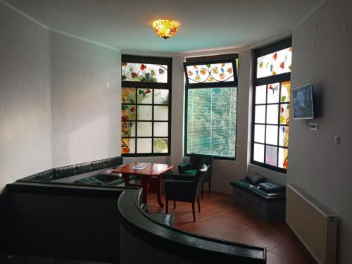 una camera con tavolo, sedie e vetrate istoriate di Hacijenda a Bajina Bašta