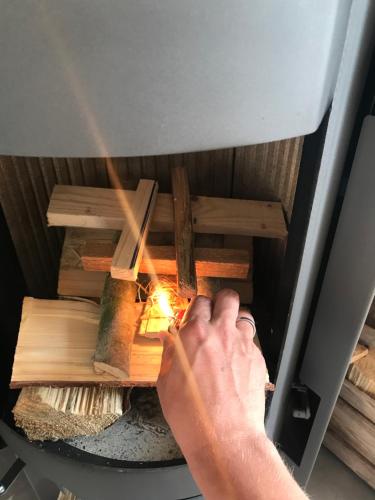 a person igniting a fire in an oven at Lytte Hytte - Ferienhaus Wingst in Wingst