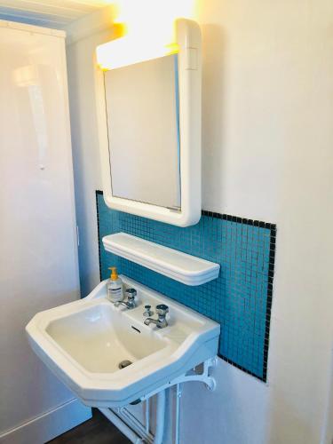 une salle de bain avec un lavabo et un miroir dans l'établissement Le Vieux Manoir, à Carolles