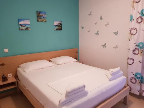 ein Schlafzimmer mit einem Bett mit weißer Bettwäsche und Schmetterlingen an der Wand in der Unterkunft Corfu Glyfada Menigos Resort 73 in Glyfada