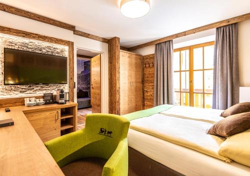 a bedroom with a bed and a desk and a television at AlpinSpa zur Post - Bergbahn im Sommer 2025 inklusive in Bad Gastein