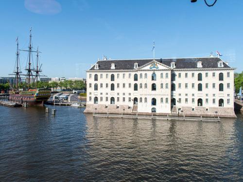 a large white building sitting on top of a body of water at SWEETS - Kortjewantsbrug in Amsterdam
