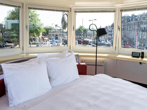 a bed with white pillows in a room with windows at SWEETS - Kortjewantsbrug in Amsterdam