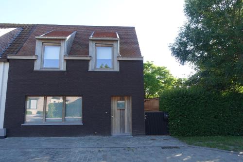 a black brick house with two windows and a door at Bed and garden in Knokke-Heist