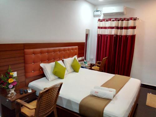 um quarto com uma cama, uma secretária e uma cortina vermelha em Medavakkam Sri Sai Residency em Chennai