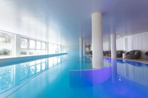 a large swimming pool in a building with a large window at Hôtel Château des Tourelles, Thalasso et piscine d'eau de mer chauffée in Pornichet