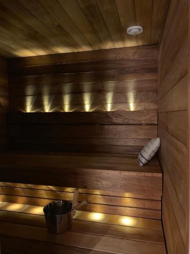 a sauna with a wooden wall and a bucket at Villa LumiHelmi A & B in Äkäslompolo