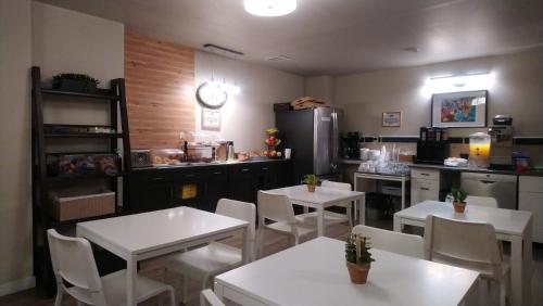 a restaurant with white tables and white chairs and a kitchen at Travelodge by Wyndham Edmonton East in Edmonton