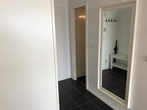 einen Flur mit Spiegel und schwarzem Fliesenboden in der Unterkunft Hanseatenhaus App. 40 in Westerland