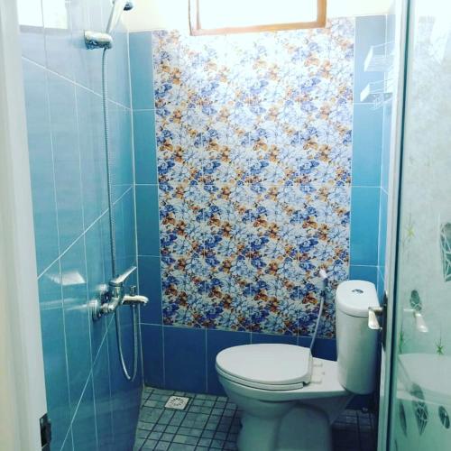a bathroom with a toilet and a blue tiled wall at ZG Homestay Solo in Sumber