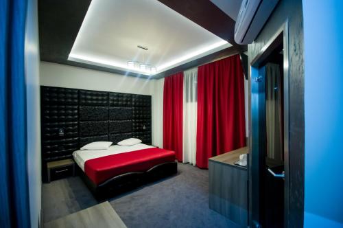a bedroom with a red bed and a bathroom at Hotel Aqua in Târgu Jiu