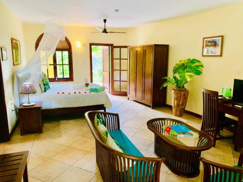 1 dormitorio con 1 cama y sillas en una habitación en Castello Beach Hotel en Grand'Anse Praslin