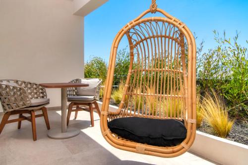 a rattan swing chair in a room with a table at Uma Ray Suites in Fira