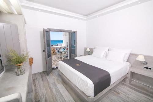 a bedroom with a bed and a balcony with the ocean at Aegean Melody Suites & Villas in Vlychada