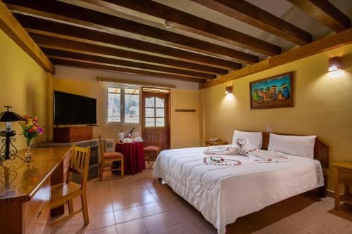 Dormitorio con cama, escritorio y TV en Art House Pisac, en Písac